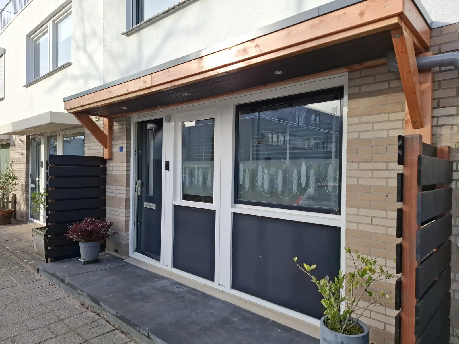 Houten luifel boven voordeur en raampartij met ingebouwde spots in de onderzijde