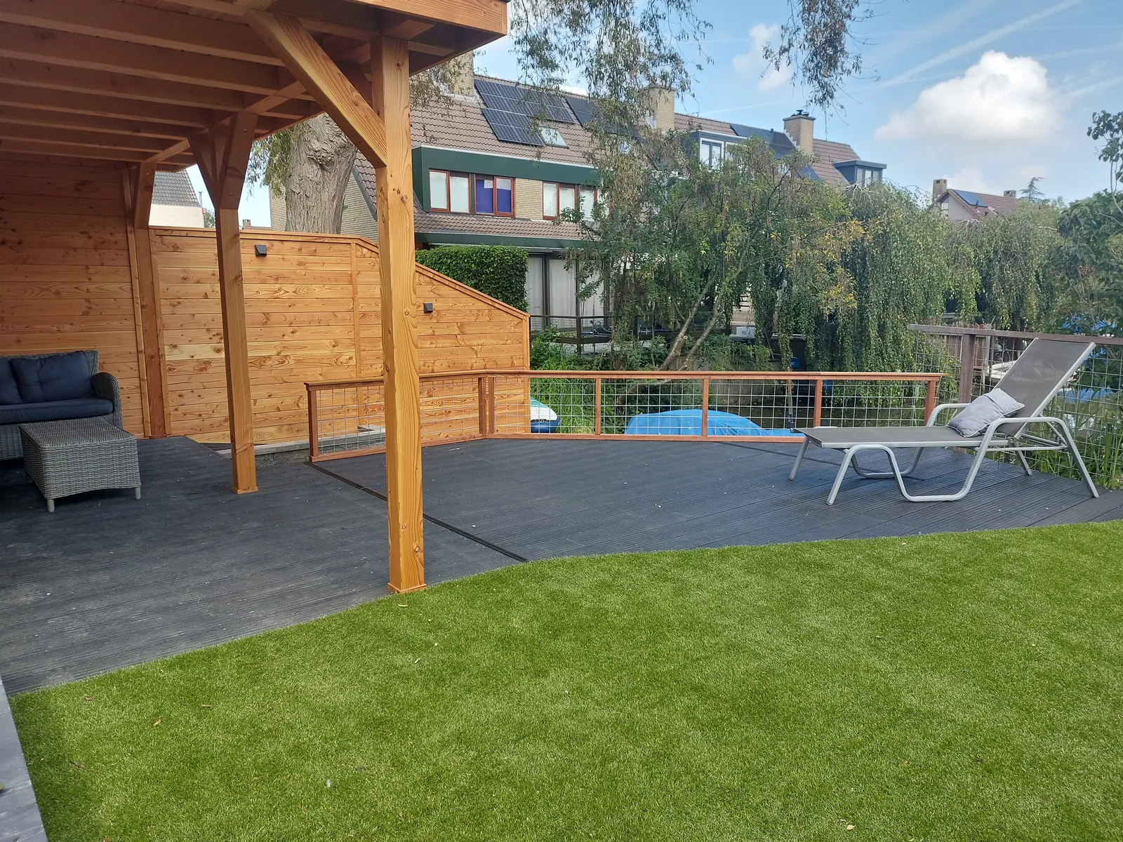 Houten overkapping met loungebank op een vlonder aan het water