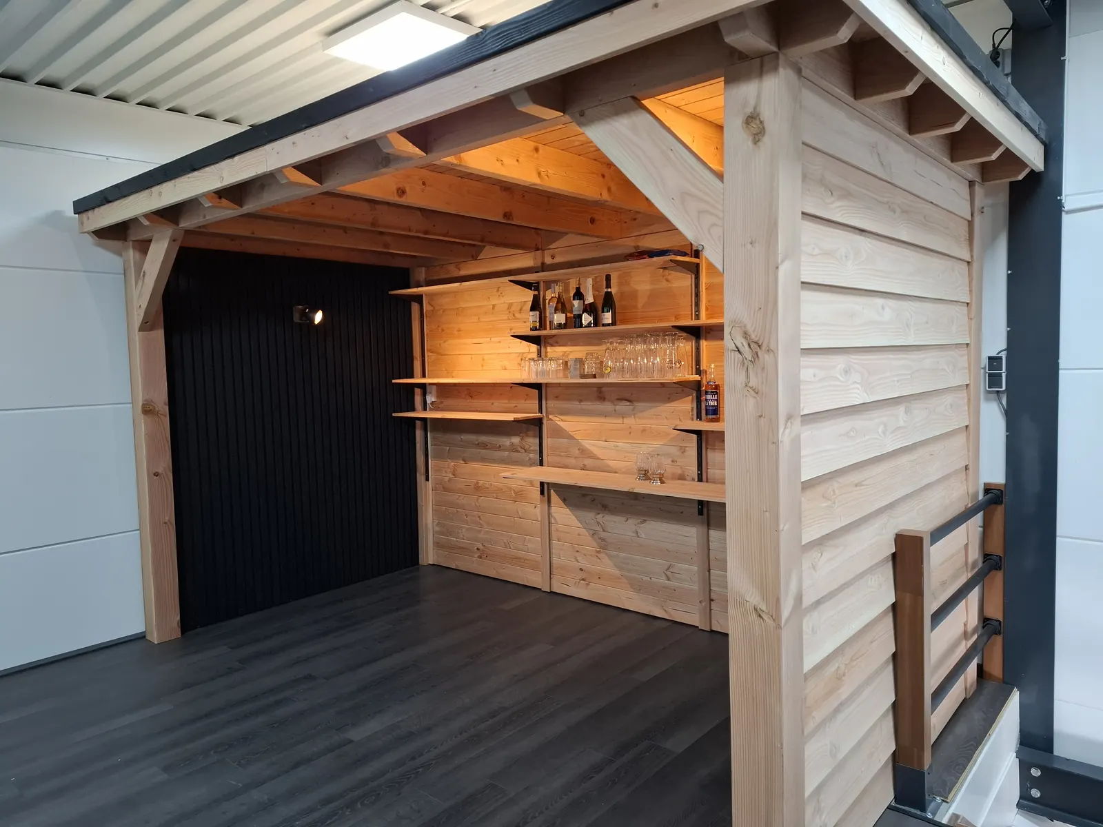 Overdekte bar met houten schappen en wanden bij een bedrijfspand