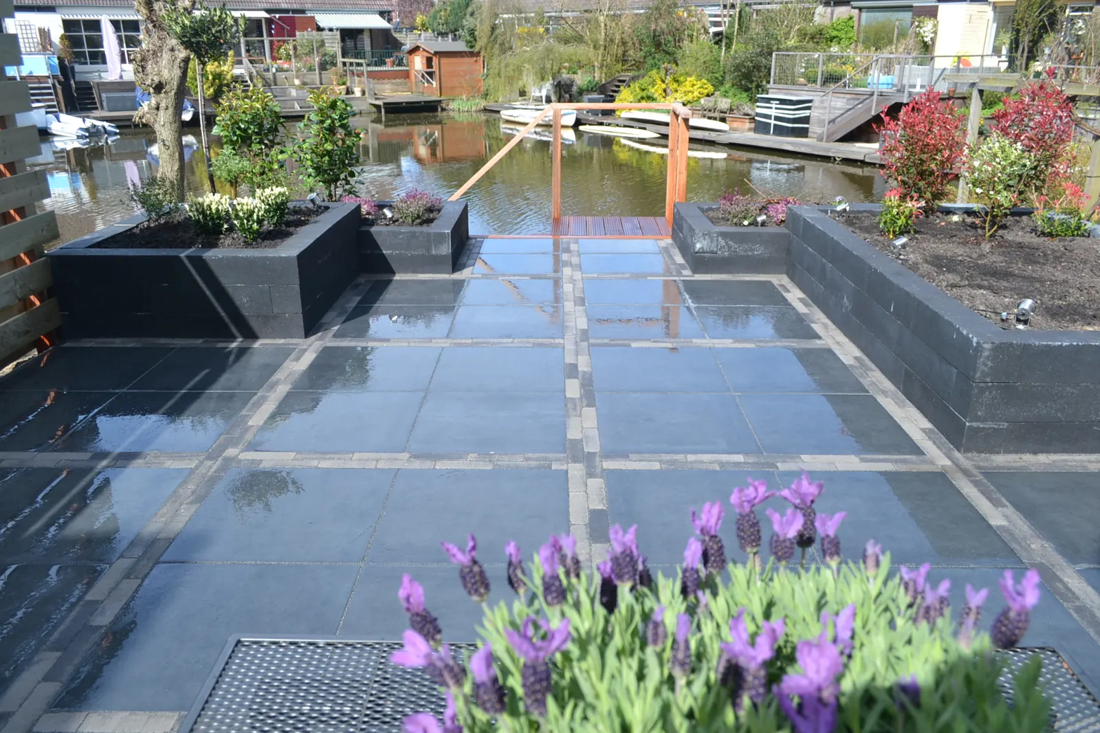 Terras van antraciet tegels met plantenbakken aan het water
