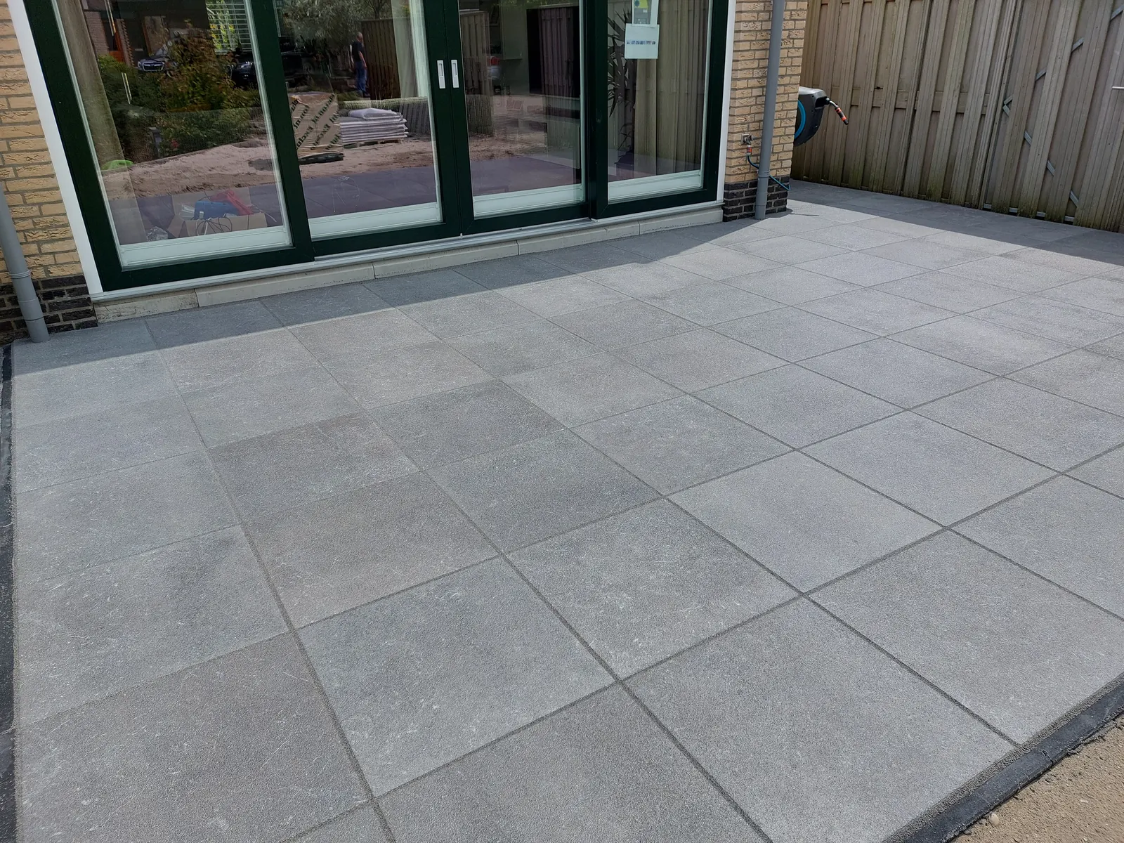 Terras van grote antraciet tegels aan de achtergevel