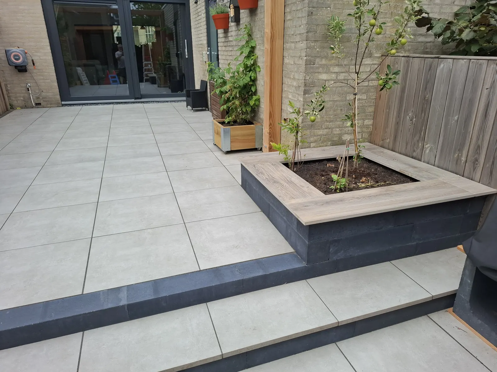 Terras met trede en houten plantenbak aan de achtergevel