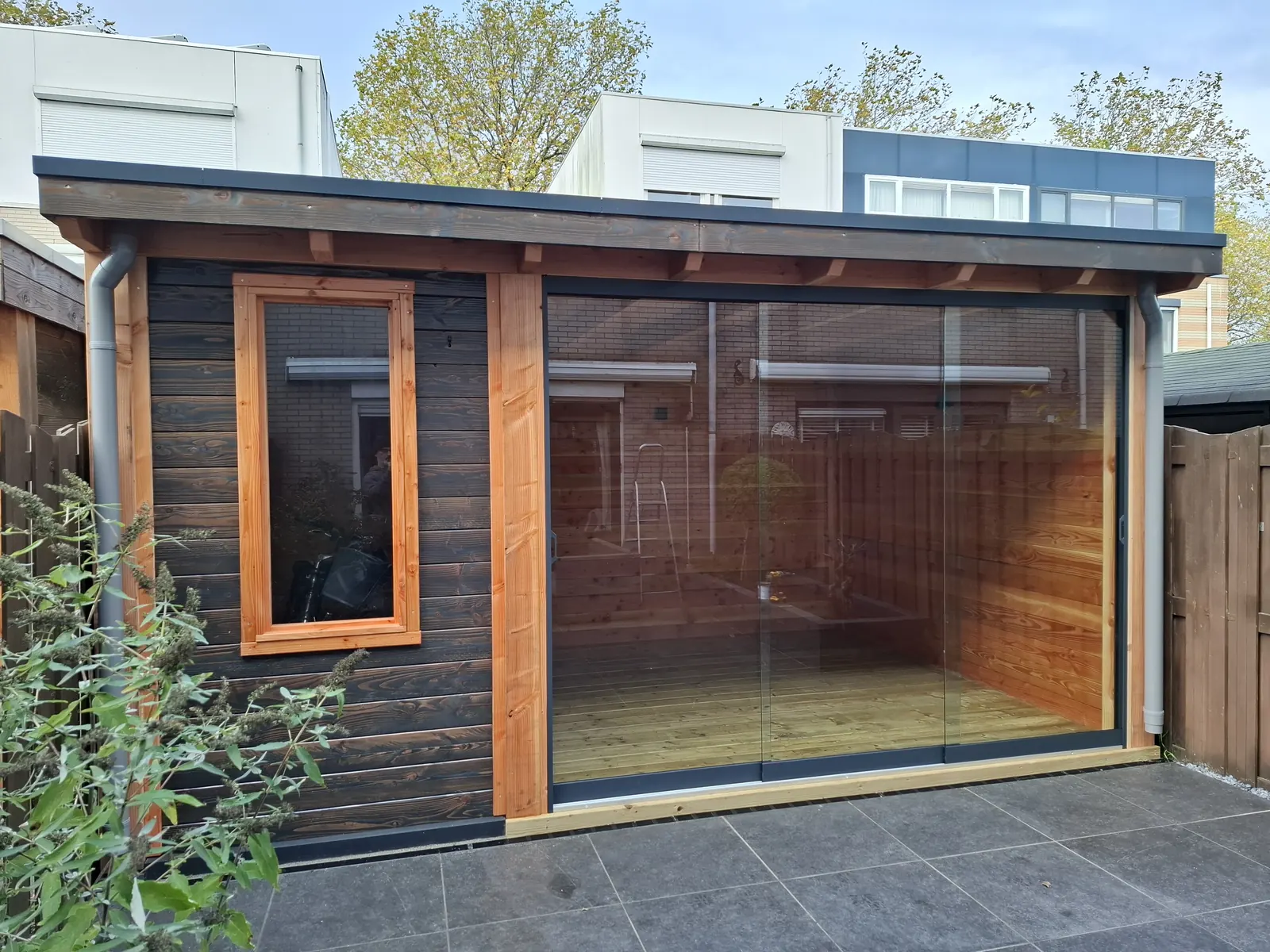 Zwart gebeitst tuinhuis met glazen schuifwand en douglas kozijnen