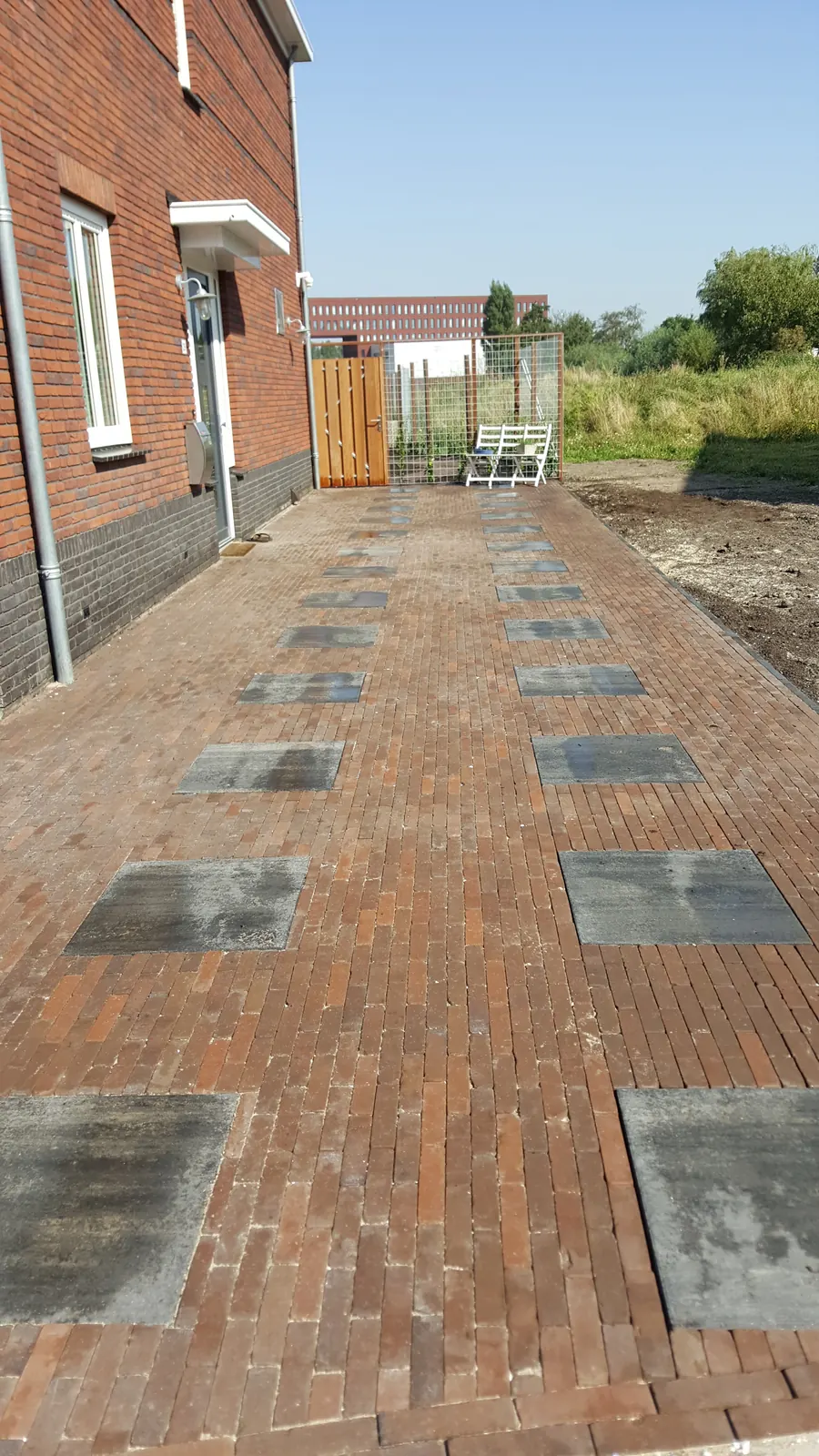 Tuinpad van gebakken klinkers met ingelegde tegels
