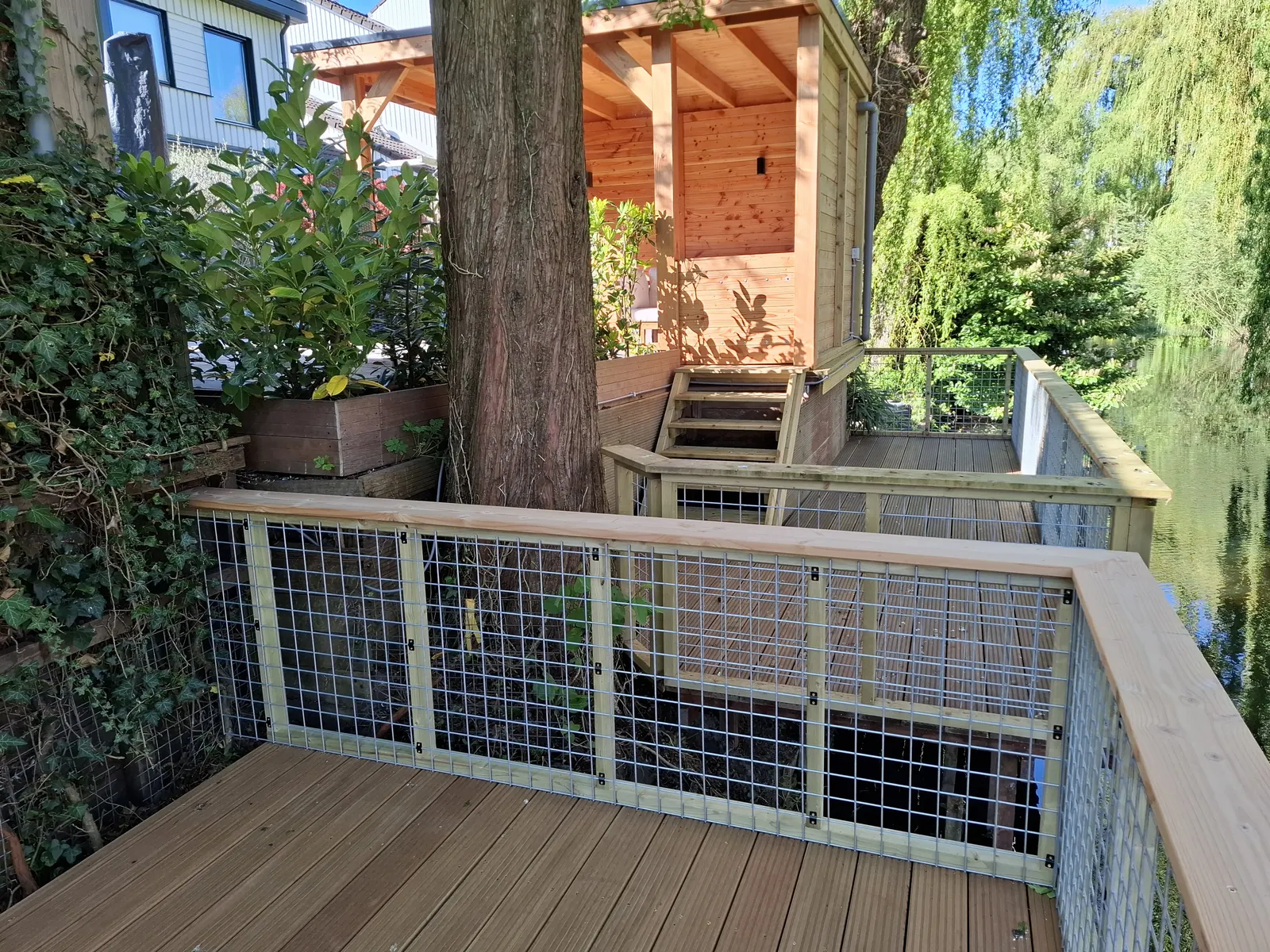 Vlonder met balustrade en een houten tuinhuis op de achtergrond