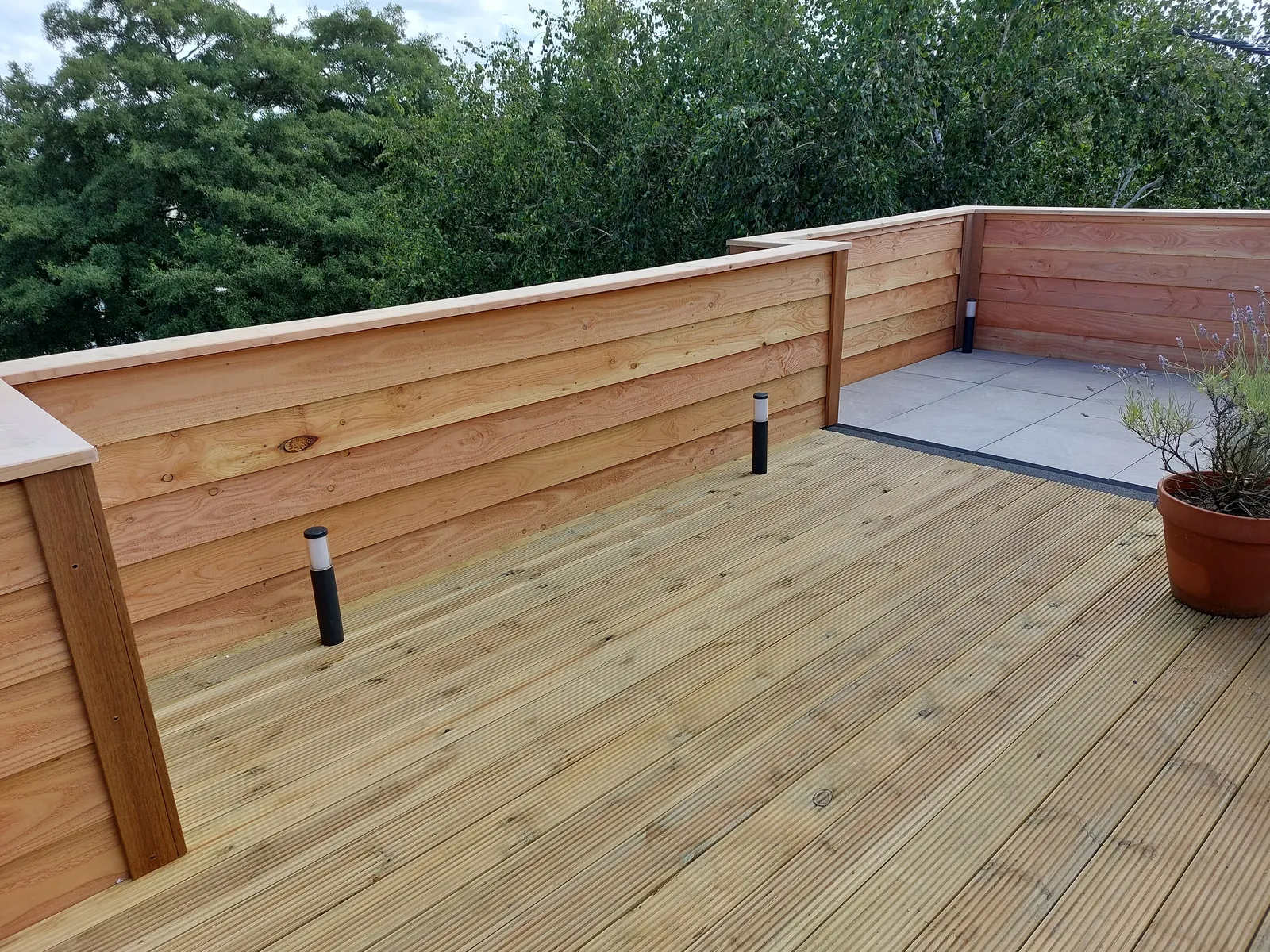 Houten vlonder met borstwering van planken en tuinspots