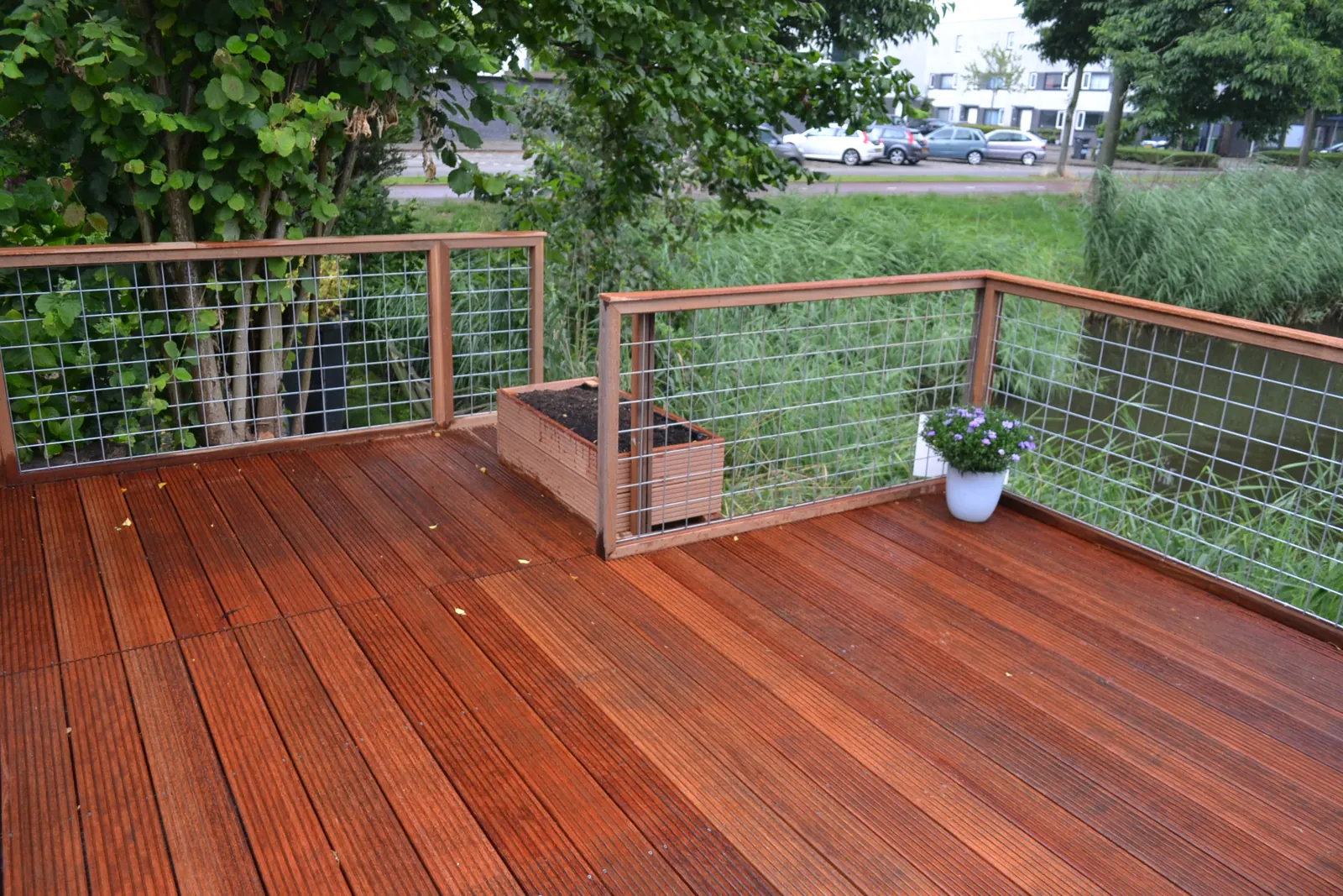 Roodbruine hardhouten vlonder met balustrade en plantenbak