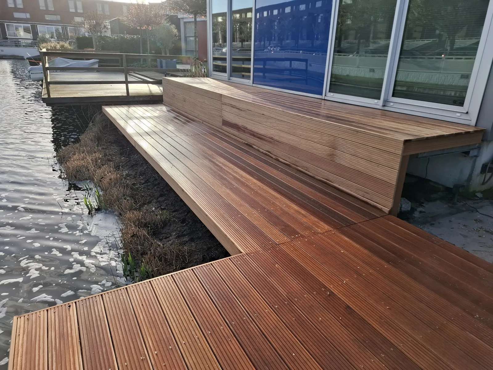 Hardhouten vlonder met ingebouwde zitbank aan het water