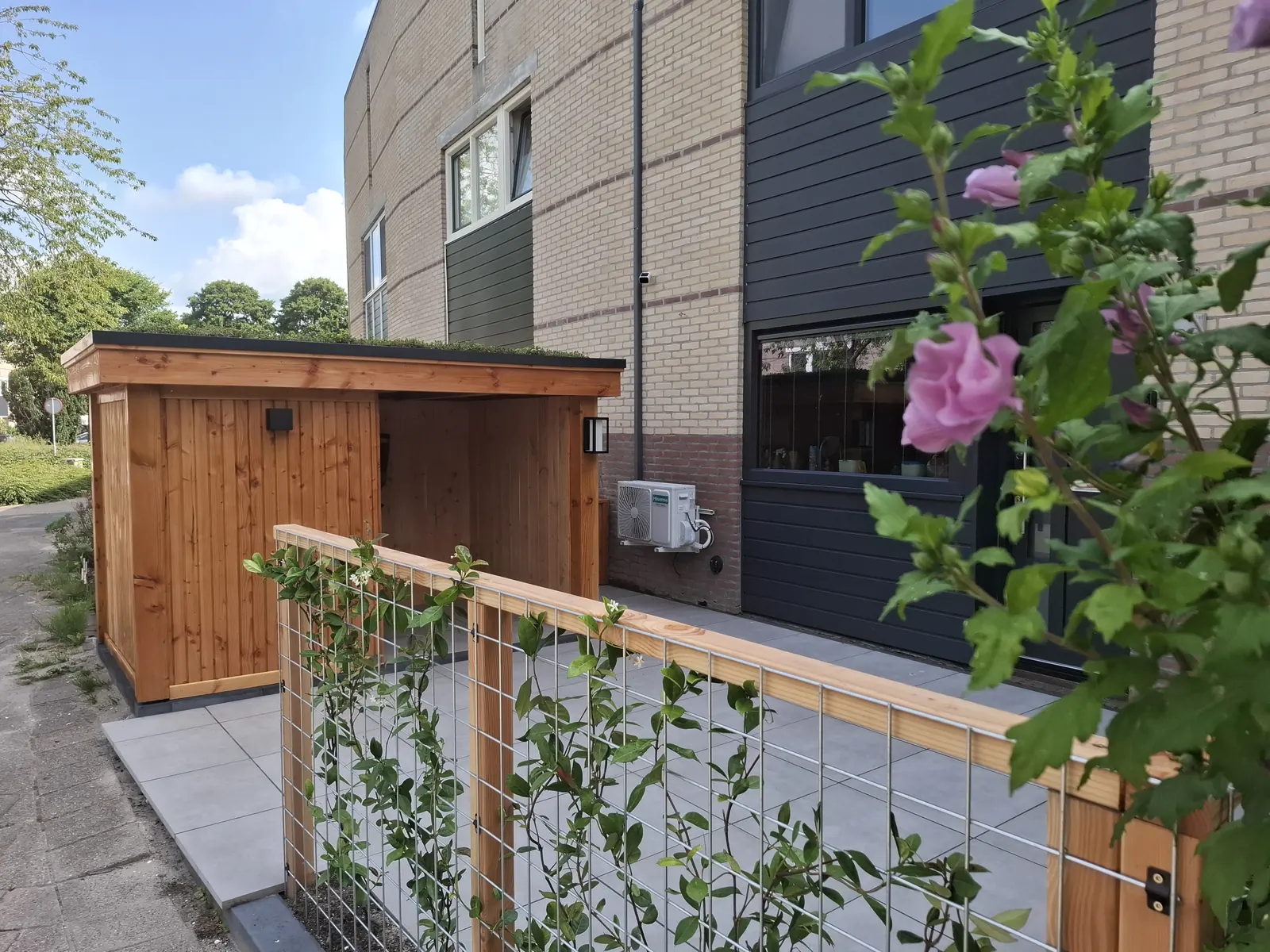 Zijtuin met houten berging en gaashek met klimplanten